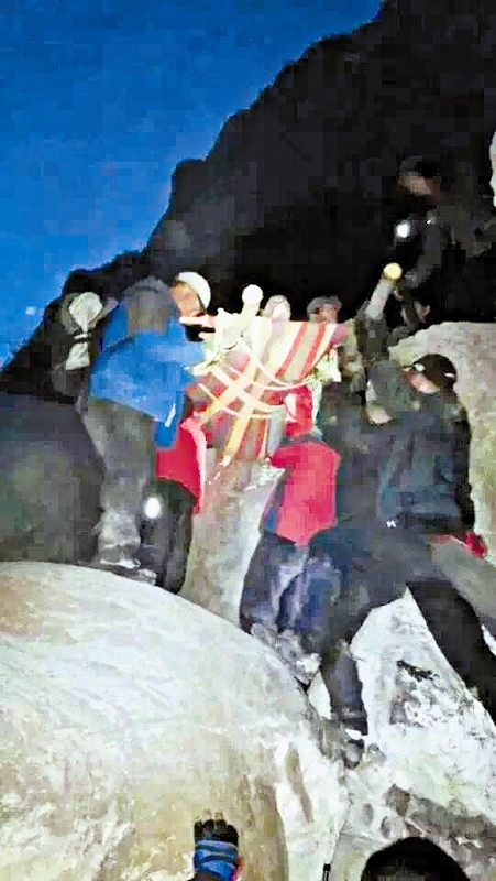 救援隊(duì)員用自制的簡易擔(dān)架抬傷者。