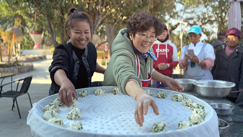 【2】旅居者趙發(fā)英(圖左二)教曼海村村民做花卷。陶思源-攝